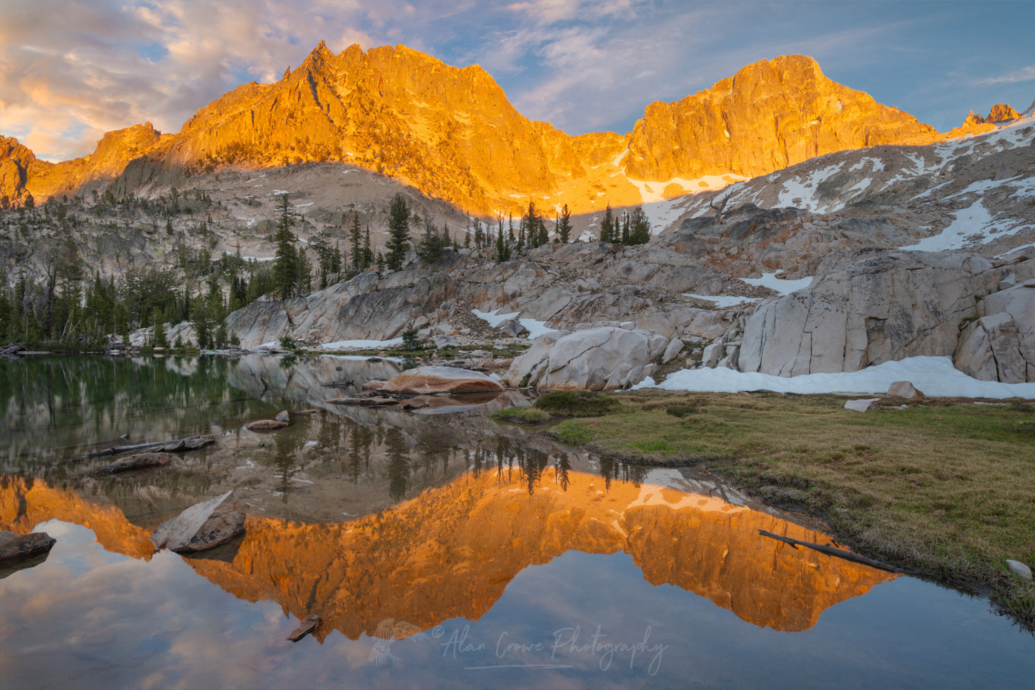 Golden light of sunset reflected on the still waters of a tarn in Upper Cramer Basin, Sawtooth Wilderness, Idaho #83712b